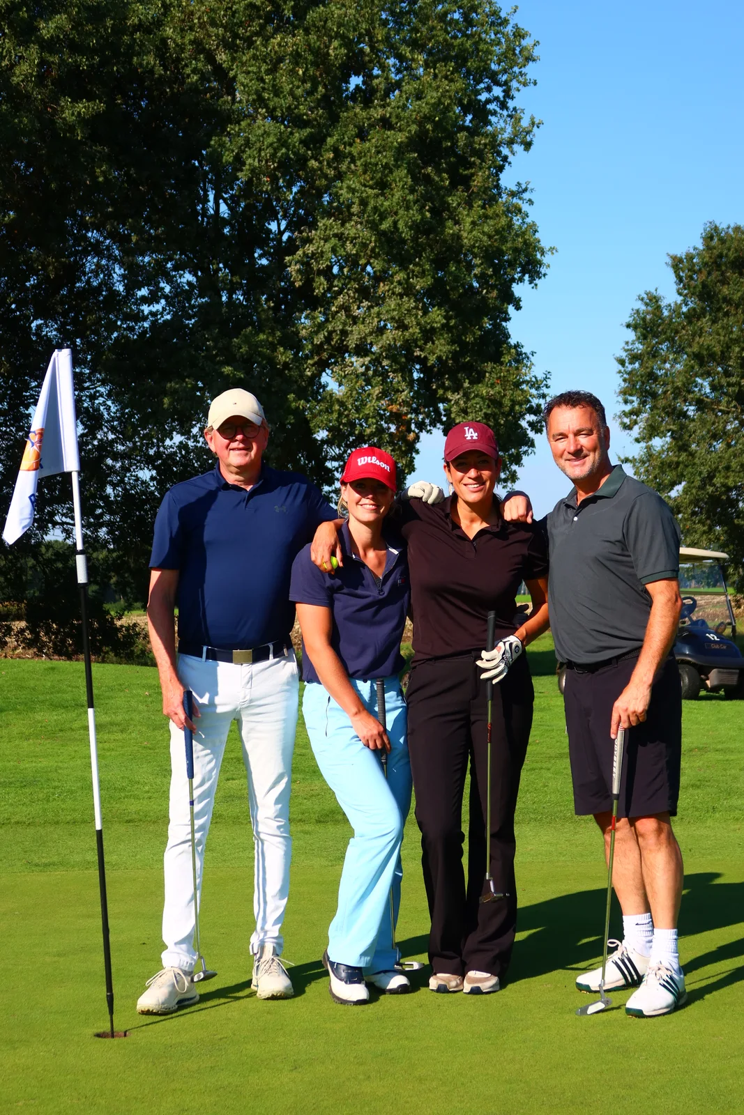 Vier deelnemers poseren samen op de golfbaan